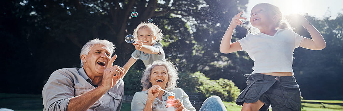 Grandparents, bubbles and children play in park happy together for fun, joy and outdoor happiness. 